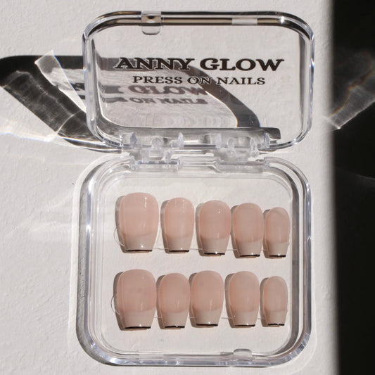 A set of press-on nails in a clear plastic box, featuring a nude base with elegant black tips for a modern take on the French manicure.