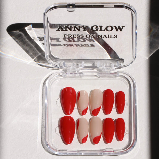 A set of press-on nails displayed in a clear plastic box, featuring a vivid red hue with playful nude accents, forming a wave-like design with a glossy finish.