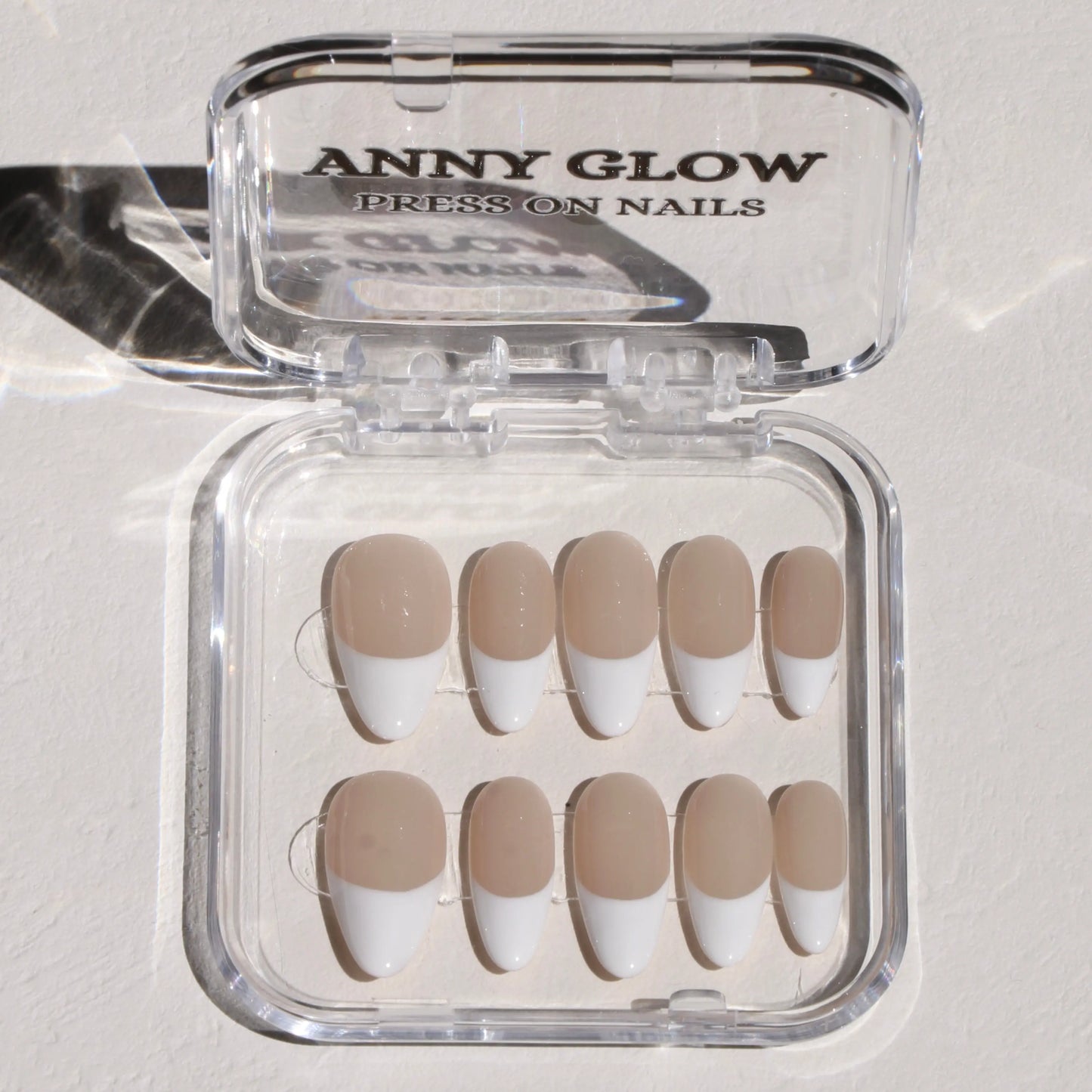  A set of press-on nails displayed in a clear plastic box, featuring a nude base with white French tips for a classic, elegant design.