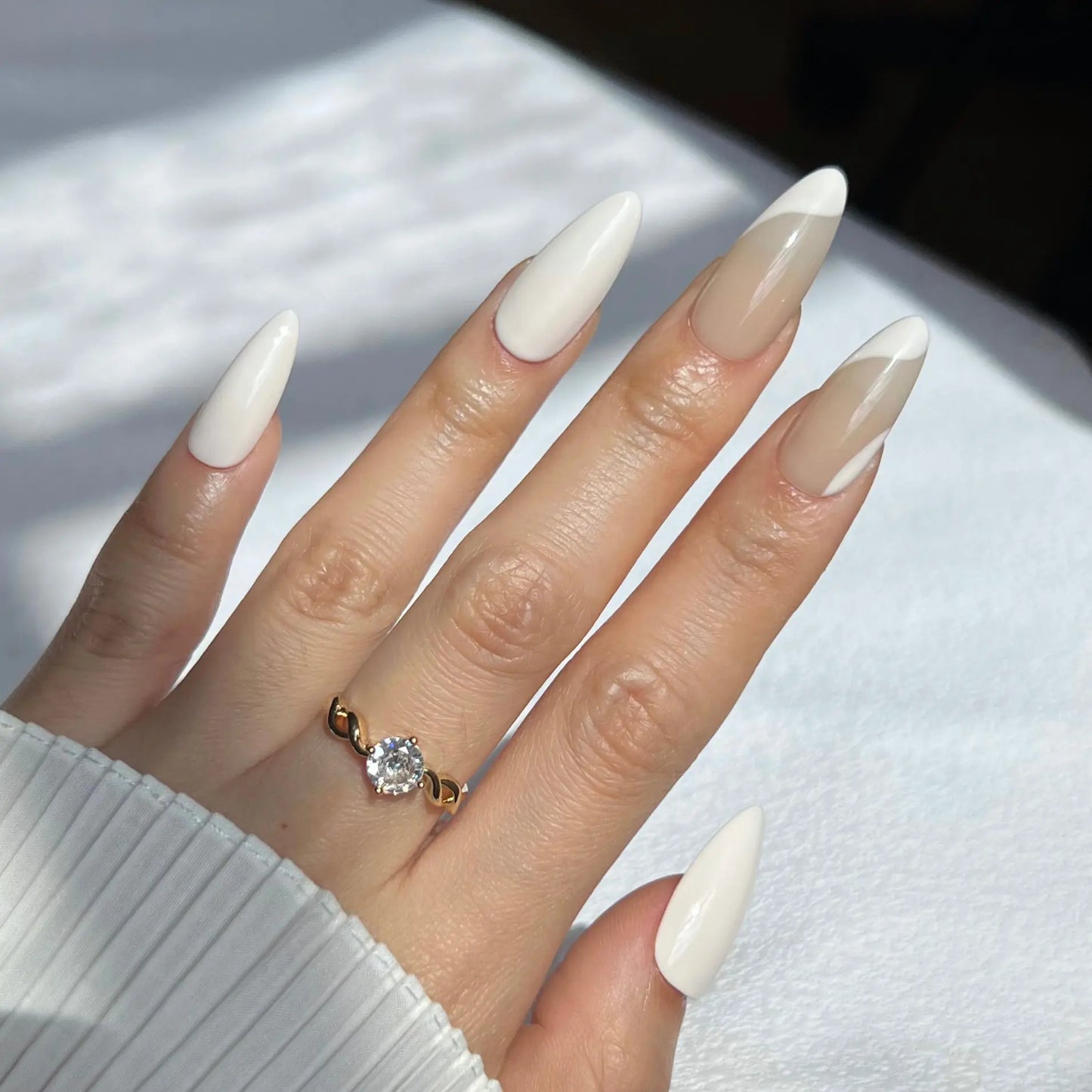 A hand showcasing ivory-colored press-on nails with nude accents, offering a refined and modern appearance.