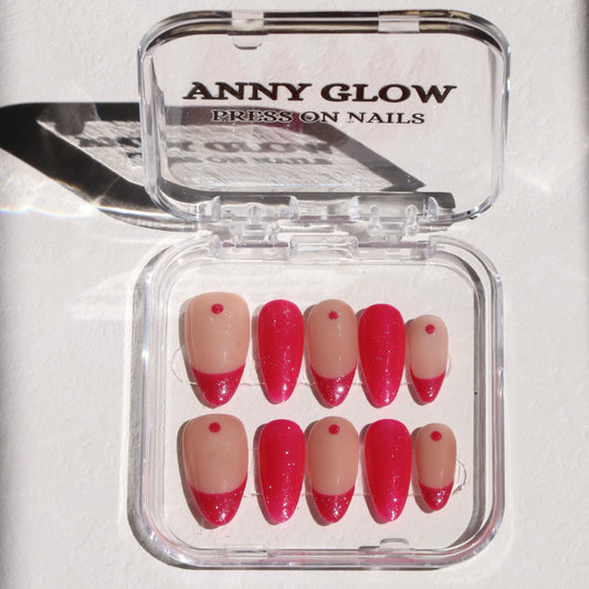 A set of press-on nails in a clear plastic box, featuring a vibrant magenta color with a glossy finish and subtle glitter details for a bold, eye-catching look.