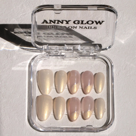 A set of press-on nails in a clear plastic box, featuring soft, pearlescent hues with subtle shimmer and wavy designs resembling the beauty of a nebula.