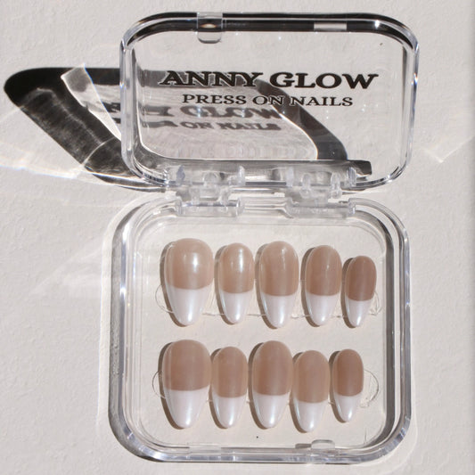 A set of press-on nails displayed in a clear plastic case, featuring a classic French tip design with a pearlescent white finish and a translucent nude base.