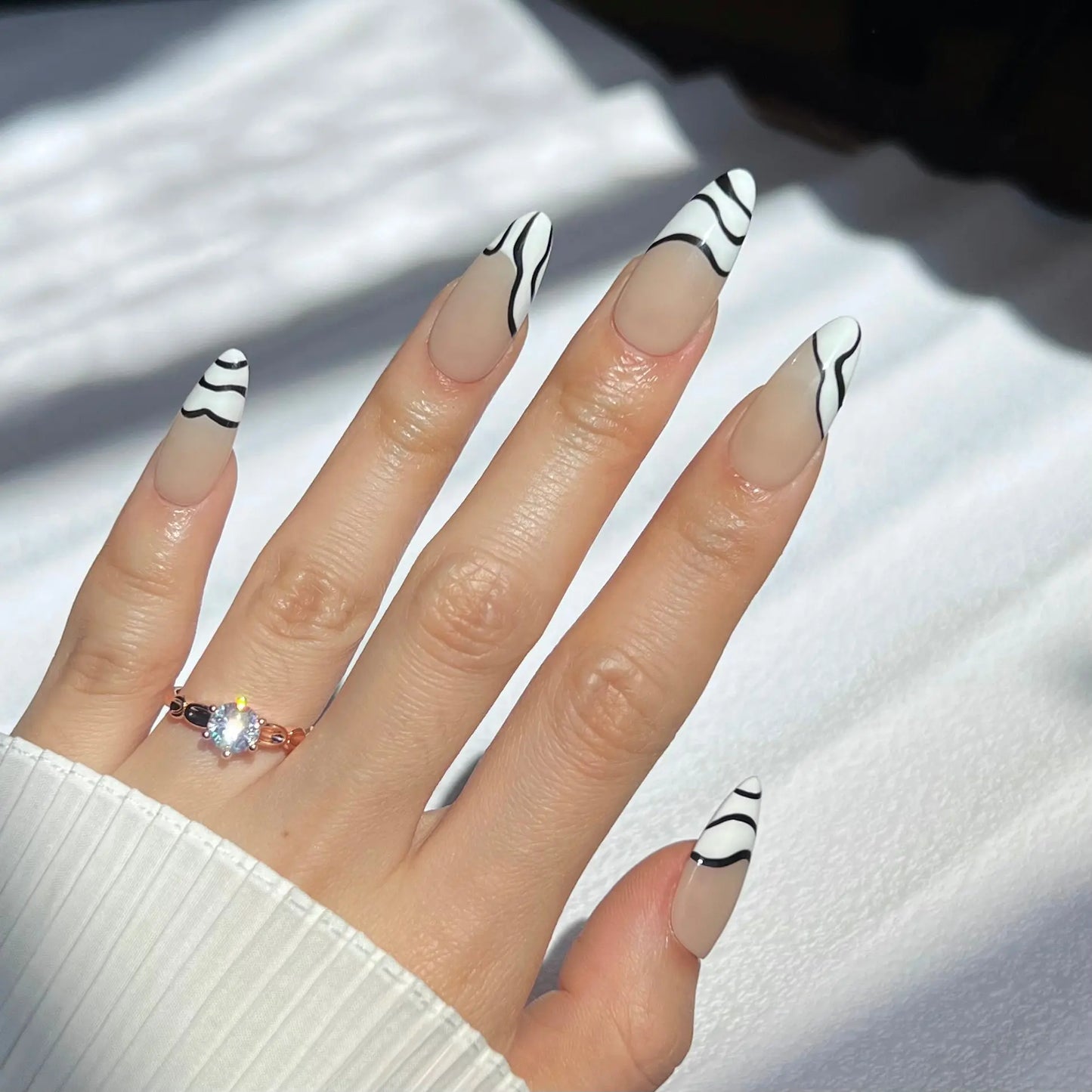 Another view of a hand showcasing zebra-striped press-on nails with a nude base, highlighting their stylish and bold pattern.